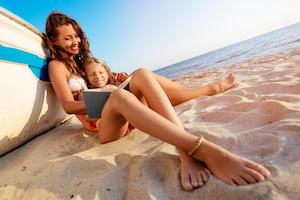 Mother reading to daughter on beach