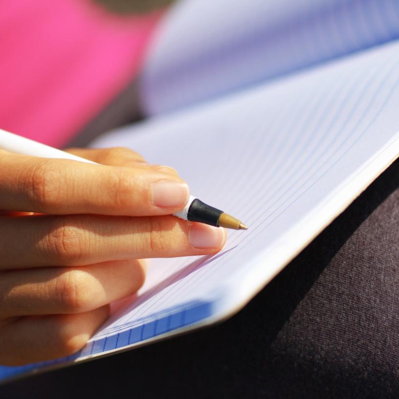 hand with pen writing in a note book